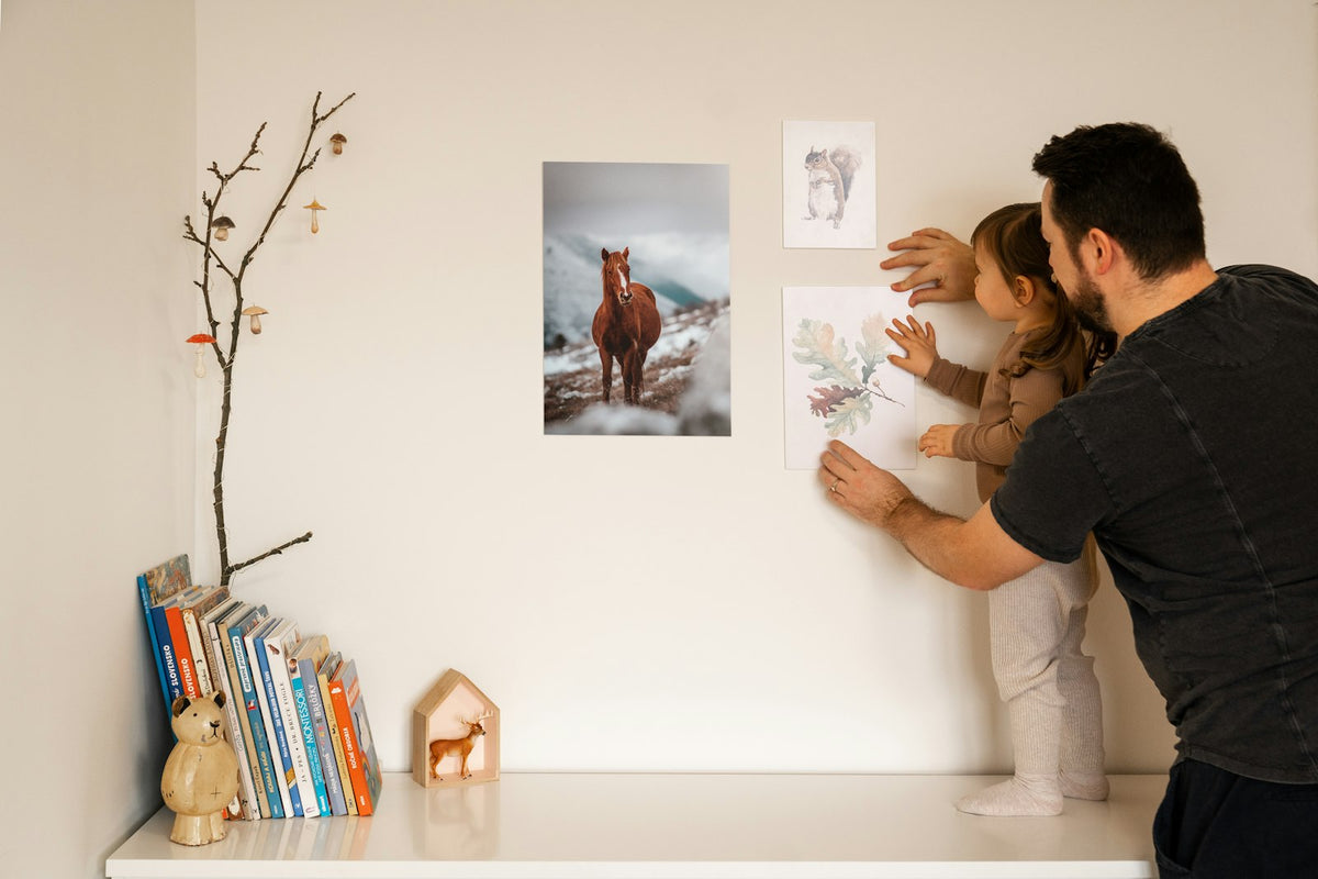 Father and young daughter looking at pictures on a wall at home