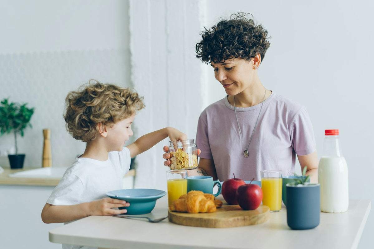 Mother and young son eating breakfast together at the kitchen table